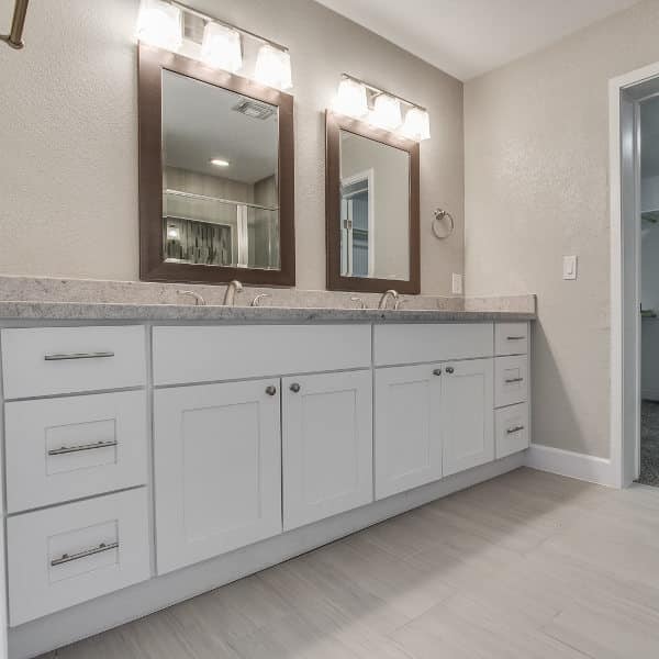 remodeled residential bathroom with white cabinets and new vanities